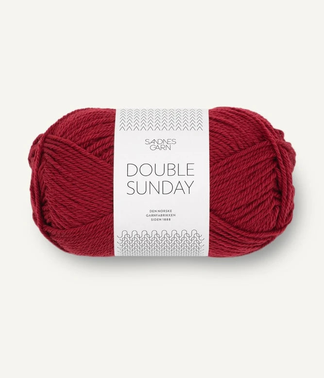 A ball of deep red coloured merino wool yarn labeled 'Double Sunday' by Sandnesgarn.