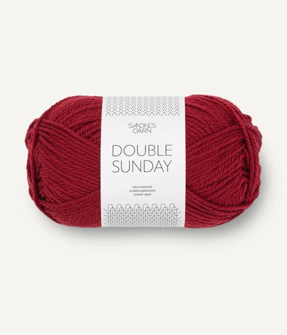 A ball of deep red coloured merino wool yarn labeled 'Double Sunday' by Sandnesgarn.