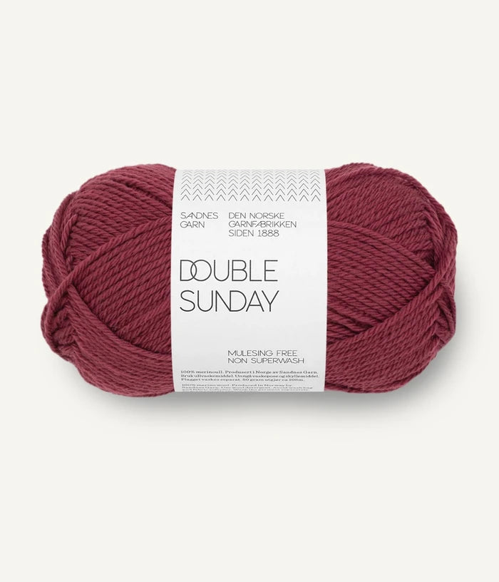 A ball of dark rose coloured merino wool yarn labeled 'Double Sunday' by Sandnesgarn.
