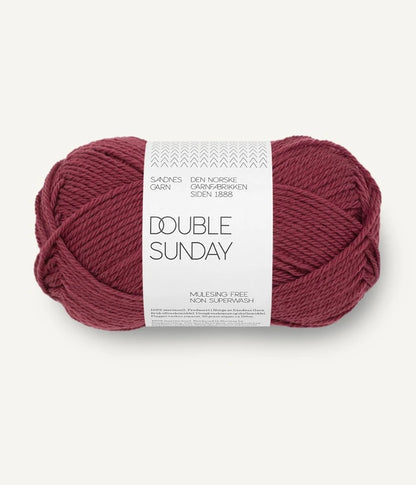 A ball of dark rose coloured merino wool yarn labeled 'Double Sunday' by Sandnesgarn.