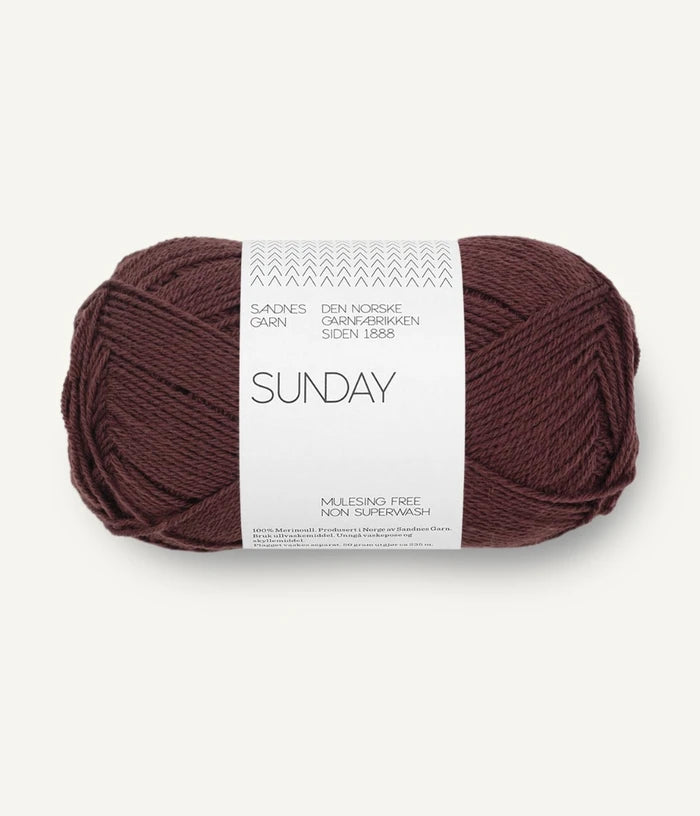 A ball of Sandnesgarn Sunday merino wool yarn in a fudge color, with packaging that includes the brand and product name.