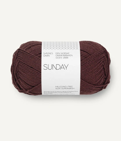 A ball of Sandnesgarn Sunday merino wool yarn in a fudge color, with packaging that includes the brand and product name.