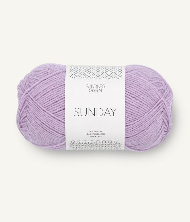 A ball of Sandnesgarn Sunday merino wool yarn in a lilac color, with packaging that includes the brand and product name.