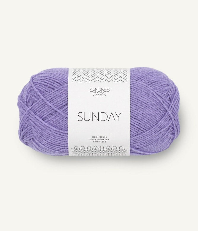 A ball of Sandnesgarn Sunday merino wool yarn in a purple color, with packaging that includes the brand and product name.