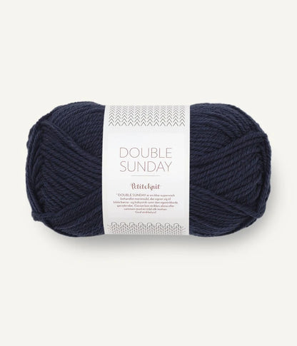 A ball of navy blue coloured merino wool yarn labeled 'Double Sunday' by Sandnesgarn.