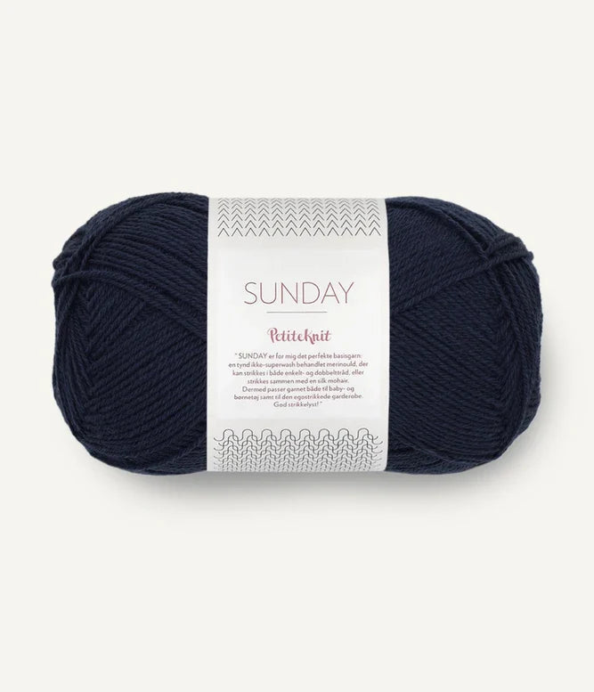 A ball of Sandnesgarn Sunday merino wool yarn in a navy blue color, with packaging that includes the brand and product name.