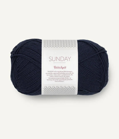 A ball of Sandnesgarn Sunday merino wool yarn in a navy blue color, with packaging that includes the brand and product name.