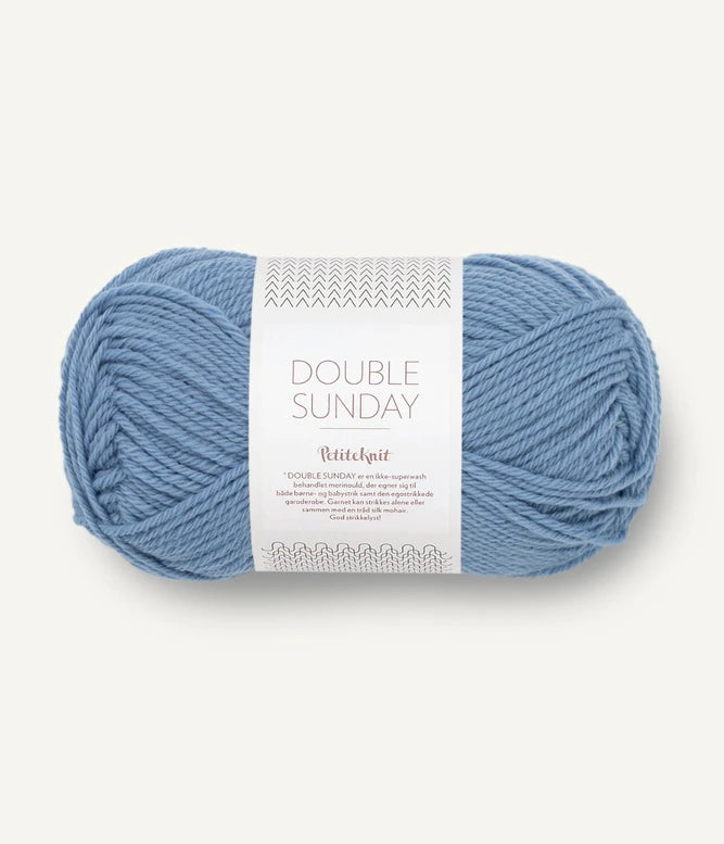 A ball of medium blue coloured merino wool yarn labeled 'Double Sunday' by Sandnesgarn.