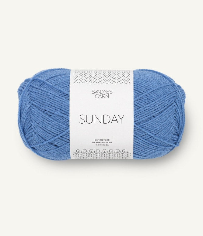 A ball of Sandnesgarn Sunday merino wool yarn in a light blue color, with packaging that includes the brand and product name.