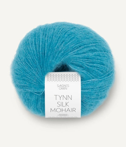 A ball of Tynn Silk Mohair yarn in a turquoise color with a 'Tynn Silk Mohair' label from Sandnes Garn