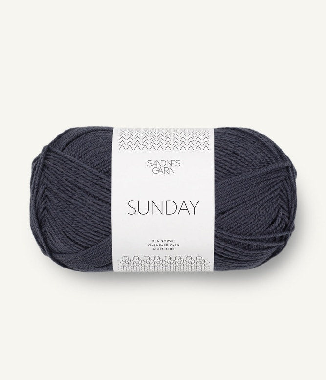 A ball of Sandnesgarn Sunday merino wool yarn in a blue-grey color, with packaging that includes the brand and product name.