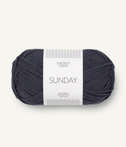 A ball of Sandnesgarn Sunday merino wool yarn in a blue-grey color, with packaging that includes the brand and product name.