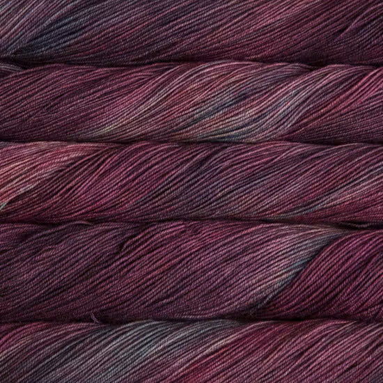 Close-up of variegated yarn in a deep plum and burgundy colorway, showing the twisted plies and subtle tonal variation.