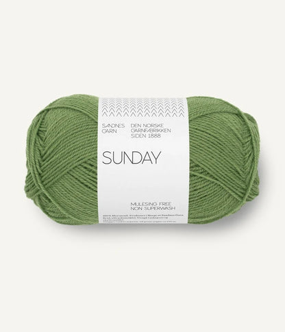 A ball of Sandnesgarn Sunday merino wool yarn in a medium green color, with packaging that includes the brand and product name.