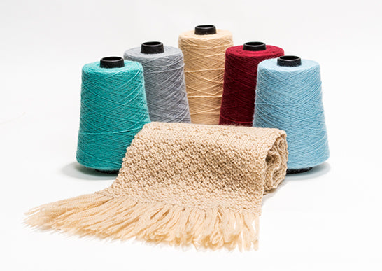Colorful yarn spools with a knitted blanket on a white background