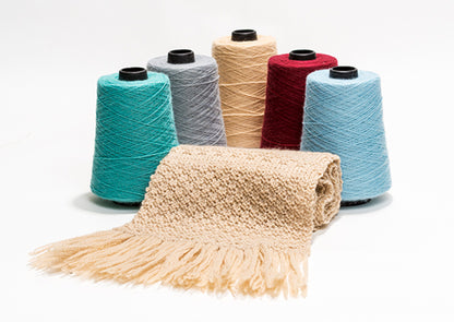 Colorful yarn spools with a knitted blanket on a white background
