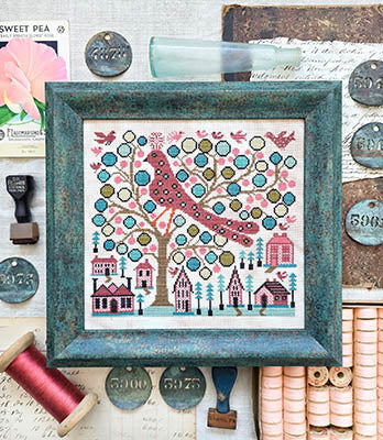Framed Cross Stitch chart with a colorful tree and bird design on a textured surface.