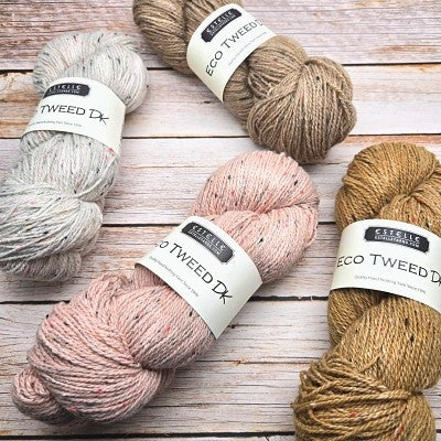 Four skeins of textured yarn arranged on a whitewashed wooden surface. The labels read 'Classic Collection' and 'Eco Tweed DK'.