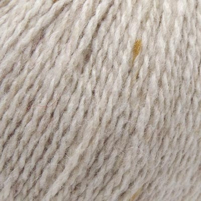 A close-up texture shot of a soft, twisted yarn in a warm off-white or cream color, showing the individual plies and a tiny hint of subtle tan flecks.