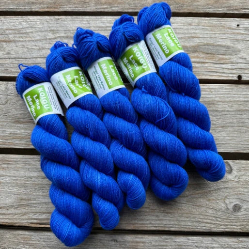 Four skeins of blue colored merino lace weight yarn labeled 'Koigu Lace Merino'. 