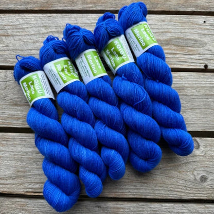 Four skeins of blue colored merino lace weight yarn labeled 'Koigu Lace Merino'. 