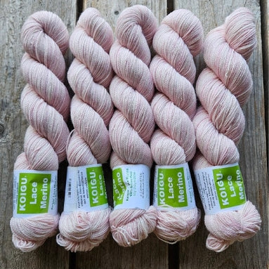 Four skeins of pale pink colored merino lace weight yarn labeled 'Koigu Lace Merino'. 