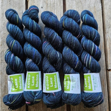 Four skeins of dark blue colored merino lace weight yarn labeled 'Koigu Lace Merino'. 