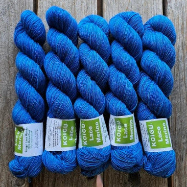 Four skeins of blue colored merino lace weight yarn labeled 'Koigu Lace Merino'. 