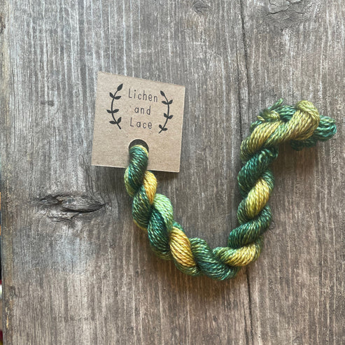 A skein of Baby Leaves green embroidery yarn labelled 'Lichen and Lace'.