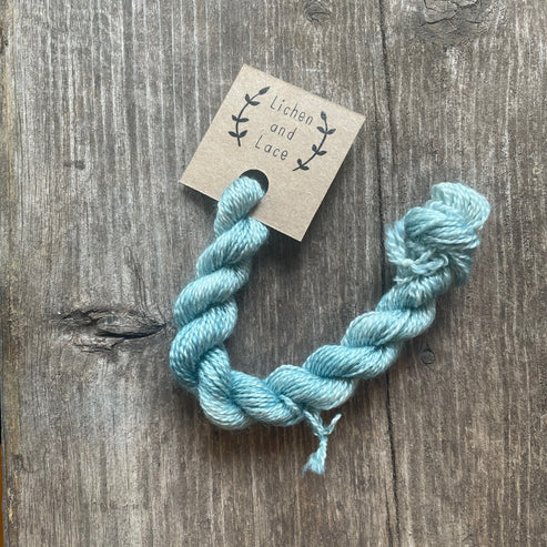 A skein of Beach Glass blue embroidery yarn labelled 'Lichen and Lace'.