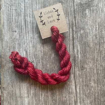A skein of Beet Root red embroidery yarn labelled 'Lichen and Lace'.