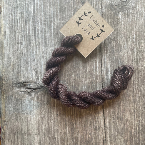 A skein of Black Walnut brown embroidery yarn labelled 'Lichen and Lace'.