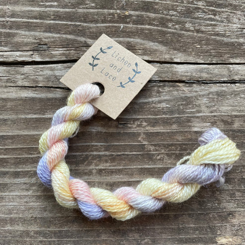 A skein of Bouquet pastel variegated embroidery yarn labelled 'Lichen and Lace'.