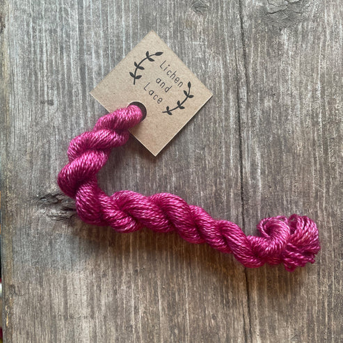 A skein of Clover pink embroidery yarn labelled 'Lichen and Lace'.