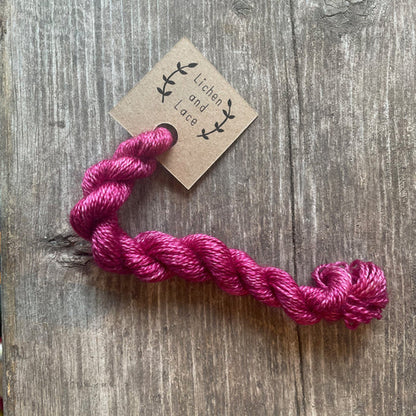 A skein of Clover pink embroidery yarn labelled 'Lichen and Lace'.