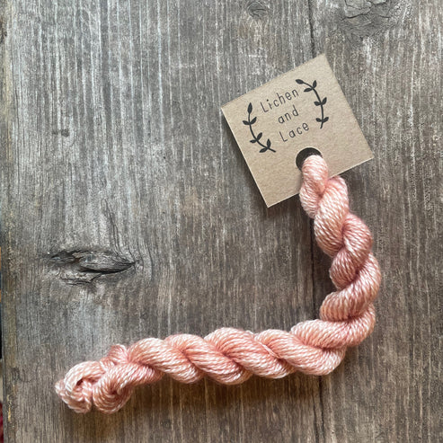 A skein of Faded Rose pink embroidery yarn labelled 'Lichen and Lace'.