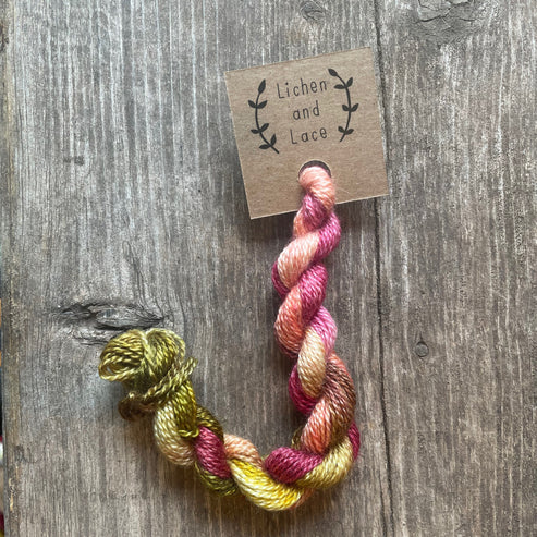 A skein of Garland pink and green embroidery yarn labelled 'Lichen and Lace'.