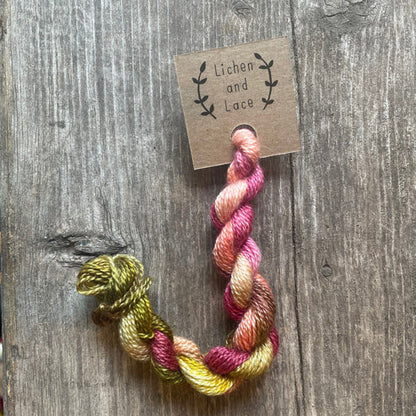 A skein of Garland pink and green embroidery yarn labelled 'Lichen and Lace'.
