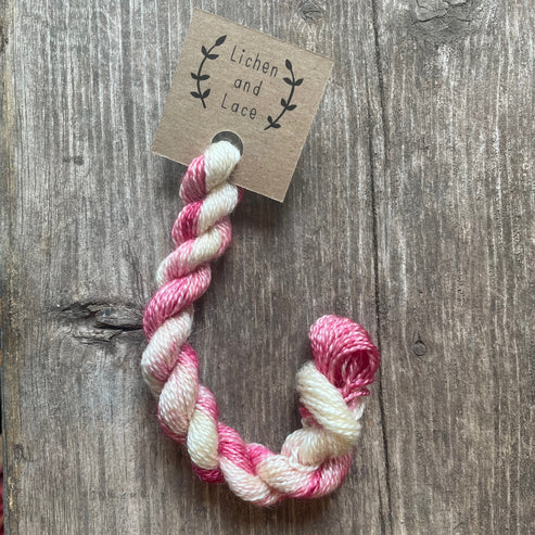 A skein of Orchid pink and white embroidery yarn labelled 'Lichen and Lace'.