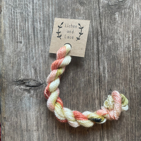 A skein of Peony pink and white embroidery yarn labelled 'Lichen and Lace'.