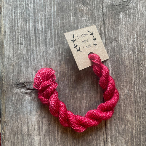 A skein of Poppy red embroidery yarn labelled 'Lichen and Lace'.