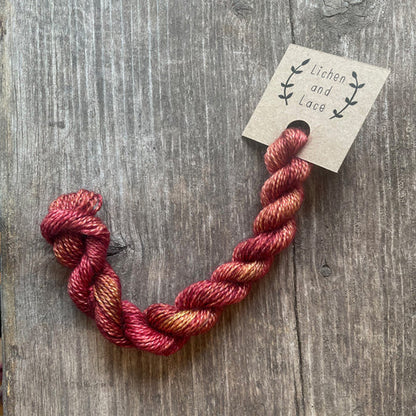 A skein of Rhubarb red embroidery yarn labelled 'Lichen and Lace'.