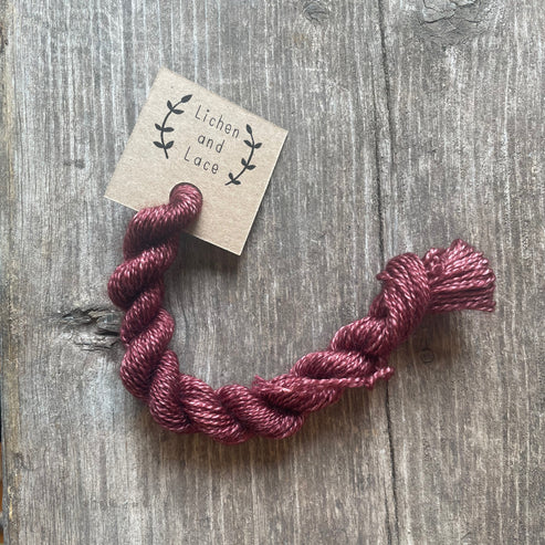 A skein of Rosewood red embroidery yarn labelled 'Lichen and Lace'.