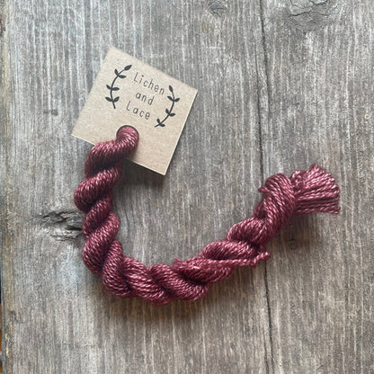 A skein of Rosewood red embroidery yarn labelled 'Lichen and Lace'.