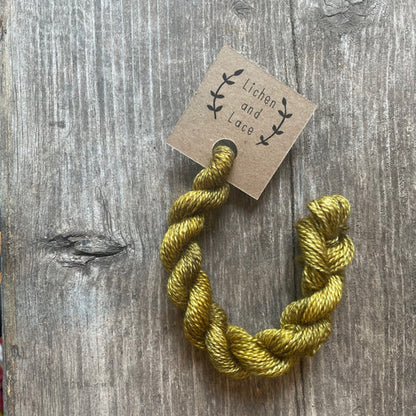 A skein of Shrub green embroidery yarn labelled 'Lichen and Lace'.