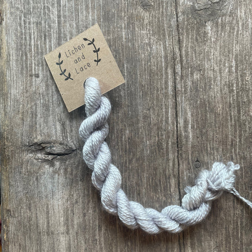A skein of silver Fox grey embroidery yarn labelled 'Lichen and Lace'.