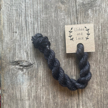 A skein of Soot grey embroidery yarn labelled 'Lichen and Lace'.