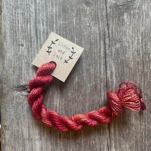 A skein of Sunburnt Lobster red embroidery yarn labelled 'Lichen and Lace'