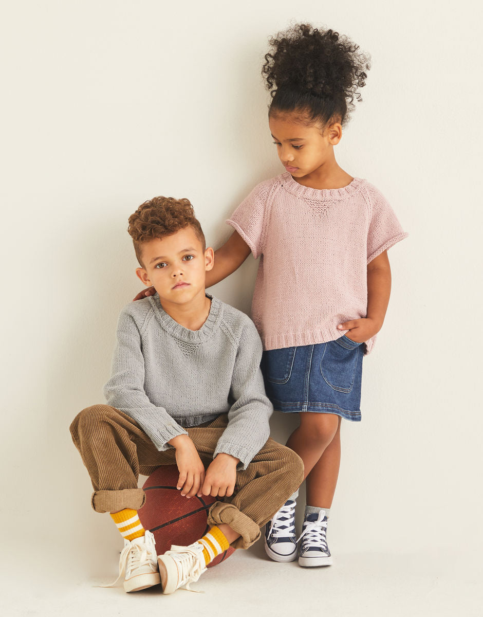 Two children wearing knitted sweatshirts, one is long sleeved and the other has short sleeves