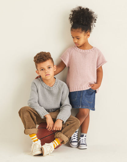 Two children wearing knitted sweatshirts, one is long sleeved and the other has short sleeves